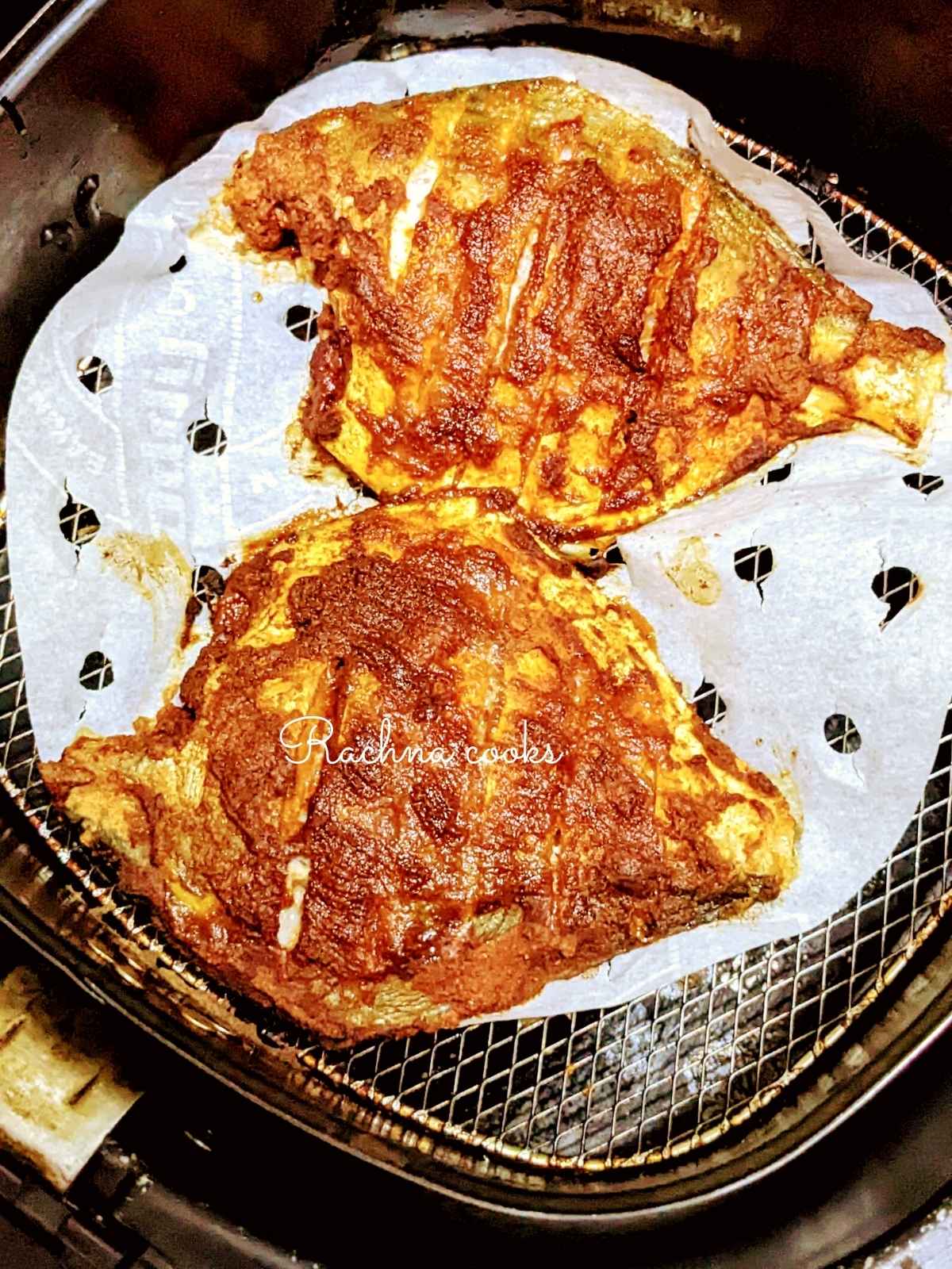 2 pomfret fish after air frying in air fryer basket.
