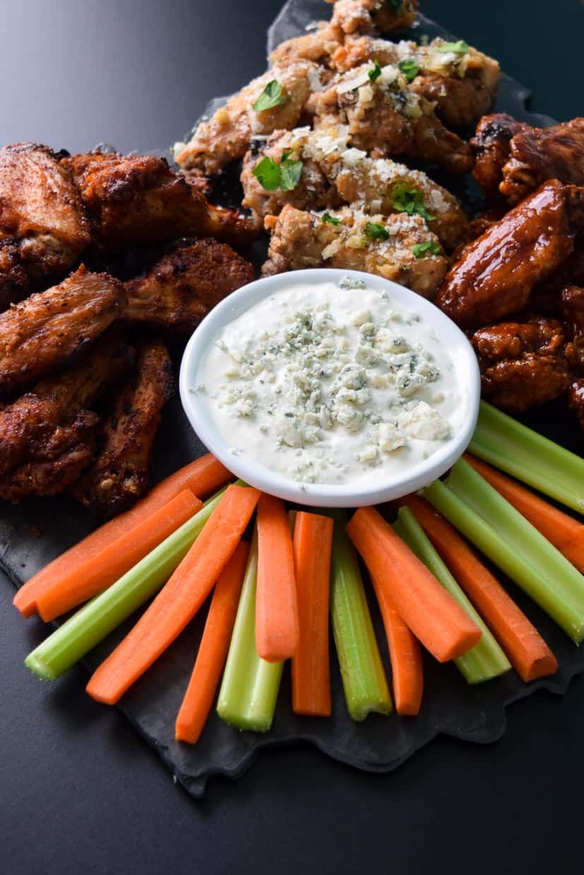 Air Fryer Game Day Wings in three flavors served on black platter with blue cheese celery and carrots up close view