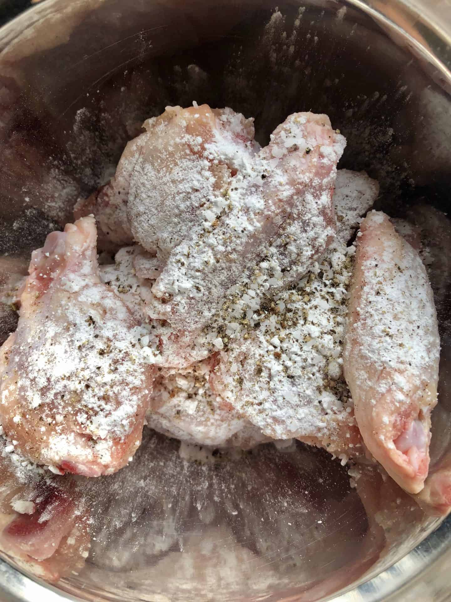 Chicken wings in bowl topped with baking powder overhead shot