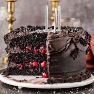 black velvet cake with a piece cut out and black frosting