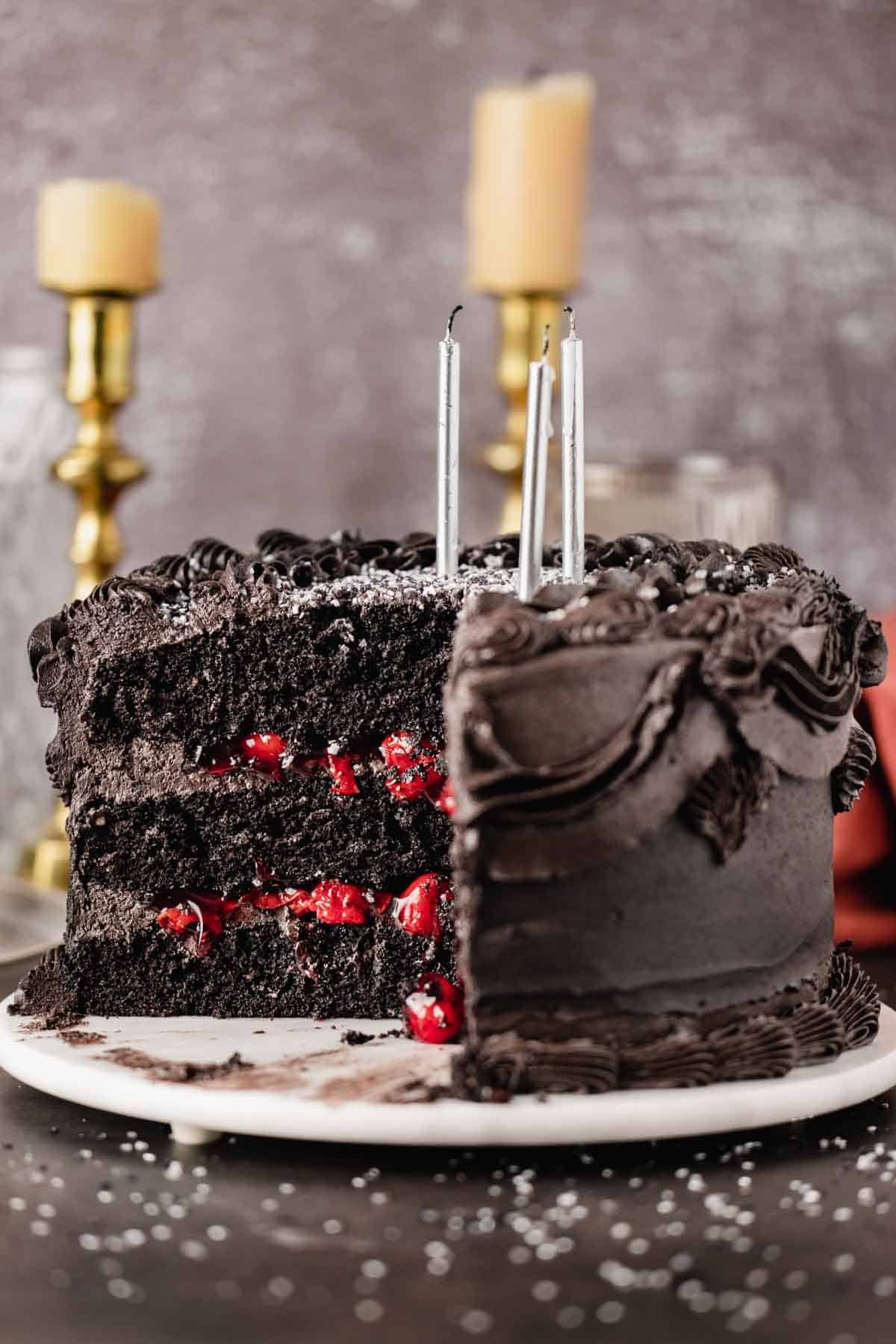 black velvet cake with a piece cut out and black frosting
