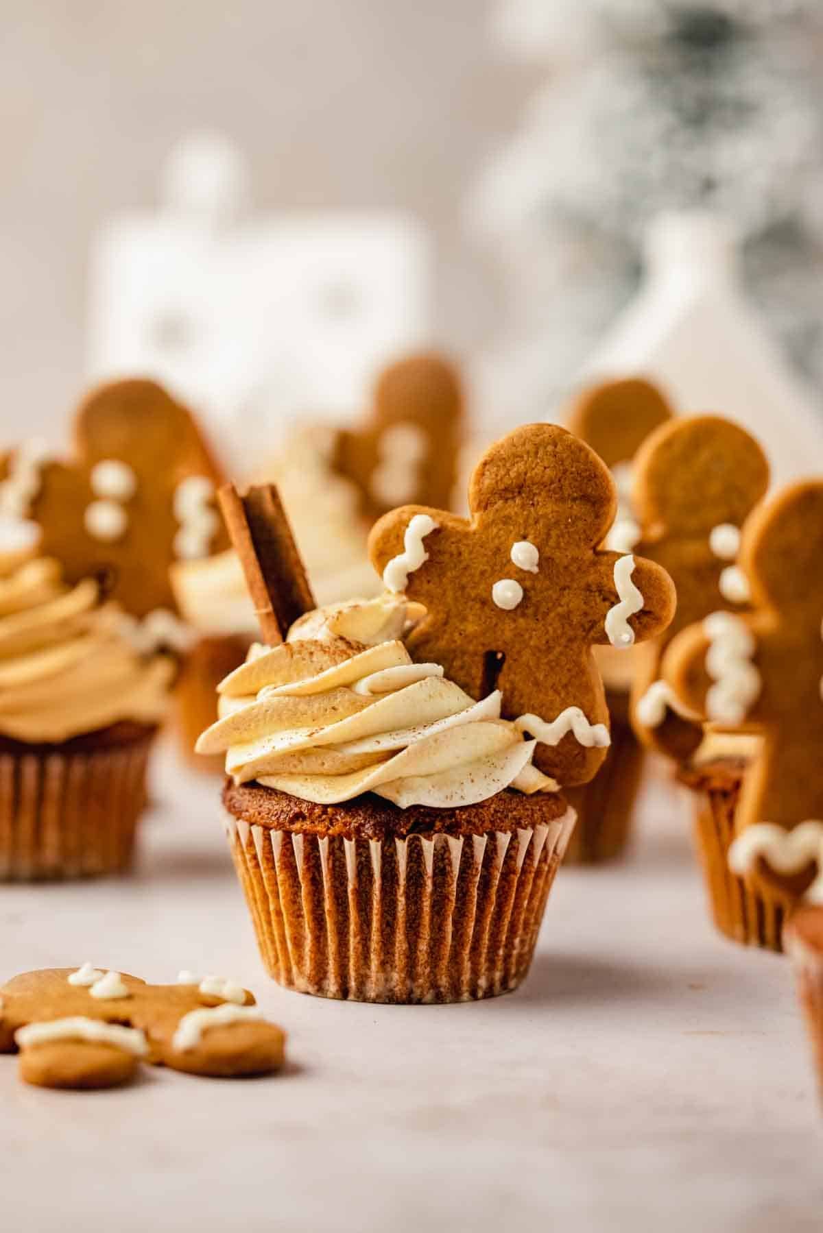 gingerbread cupcakes with gingerbread frosting and mini gingerbread men with evergreen tree in the back