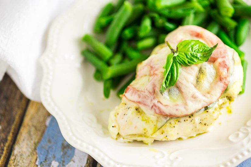 Quick and easy Baked Caprese Chicken features cheesy chicken breast with basil pesto, basil leaves, and a slice of fresh tomato for a fresh and healthy weeknight dinner!