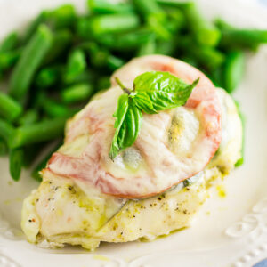 Quick and easy Baked Caprese Chicken features cheesy chicken breast with basil pesto, basil leaves, and a slice of fresh tomato for a fresh and healthy weeknight dinner!
