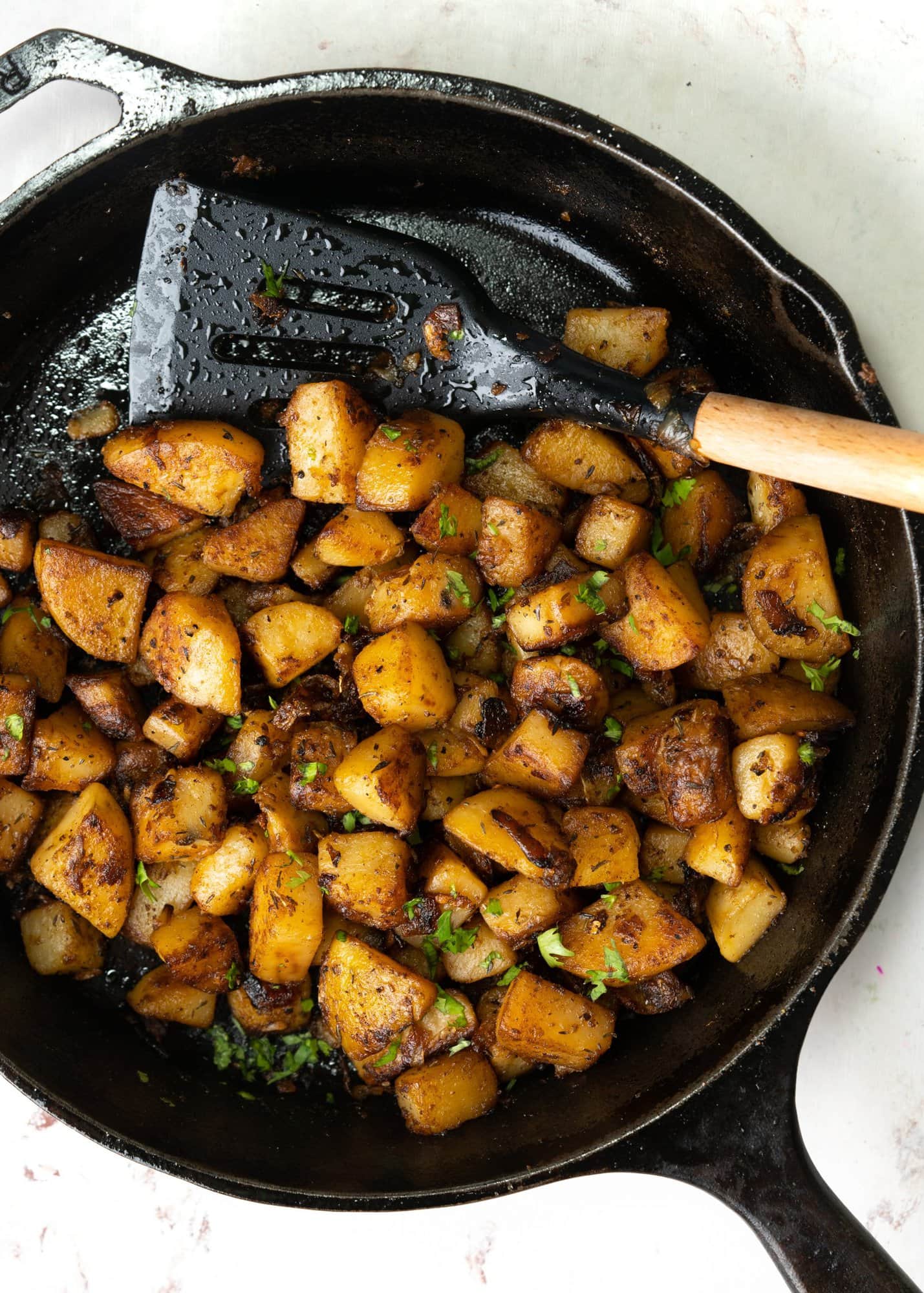 Top view of crispy breakfast potatoes made in a skillet and shown with a spatula.