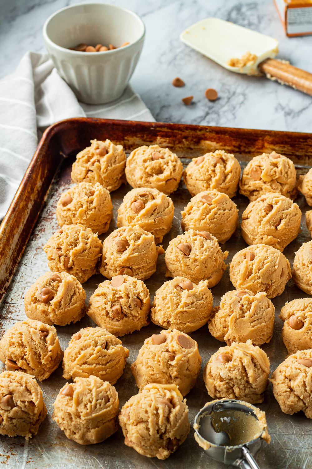 Rows of raw butterscotch chip cookie dough balls on a pan 
