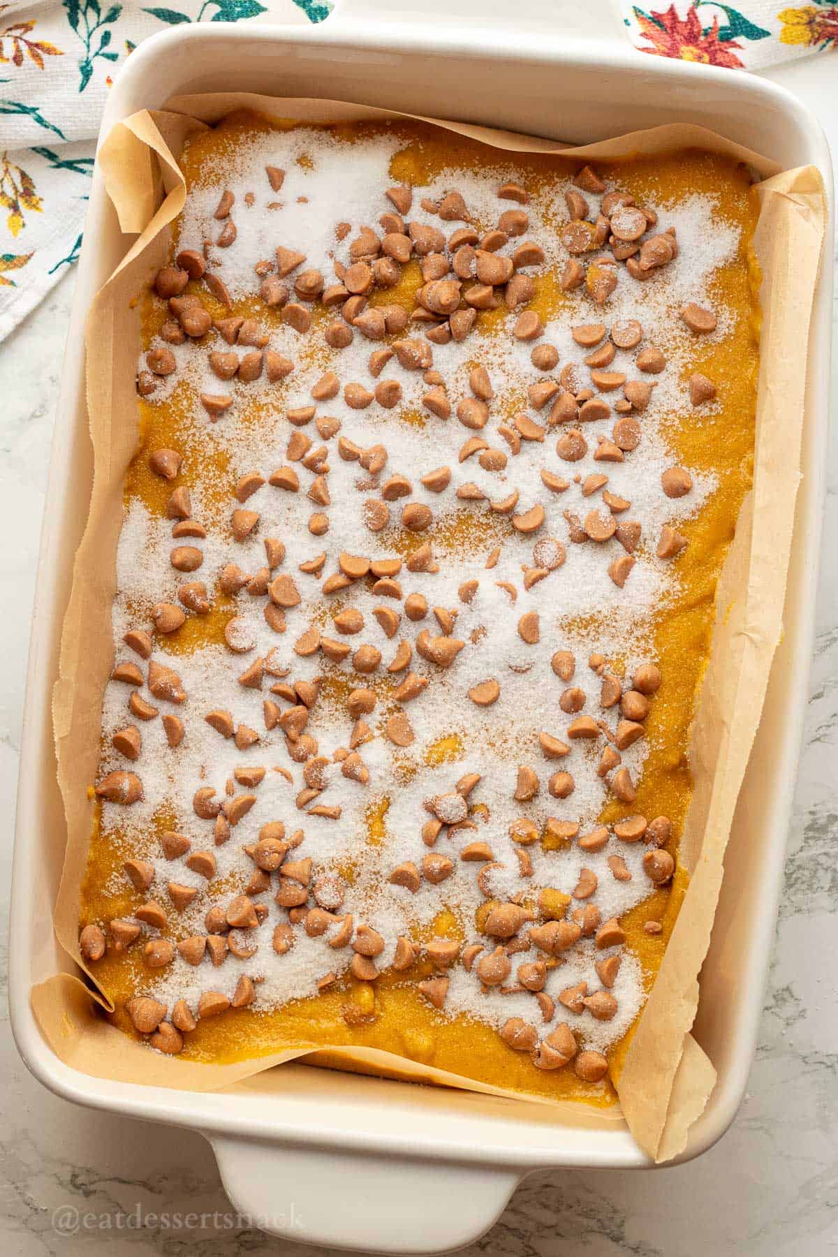 Sugar and butterscotch chips on cake batter in pan.