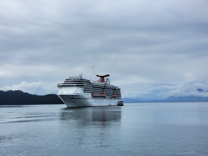 Carnival Cruise ship with clouds and mountains behind it in alaska 