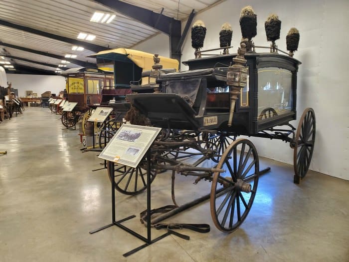 museum with historic carriages and signs  in front of them. 