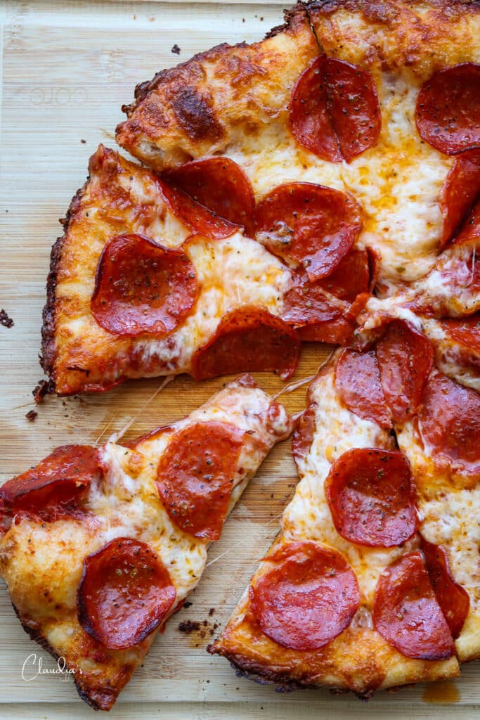 cast iron pan pizza sliced into wedges on cutting board 