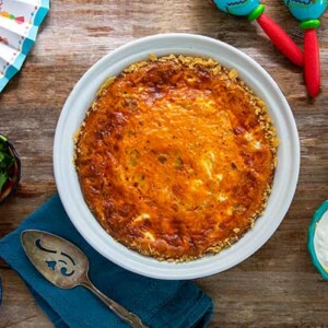 Overhead view of Chips and Salsa Quiche on a wood background with Mexican decor surrounding it