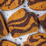 Slices of pumpkin chocolate marble bread on a sheet of baking parchment.