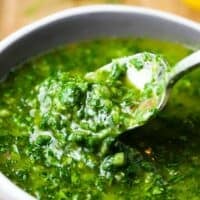 A small bowl of chimichurri with a spoon digging in.