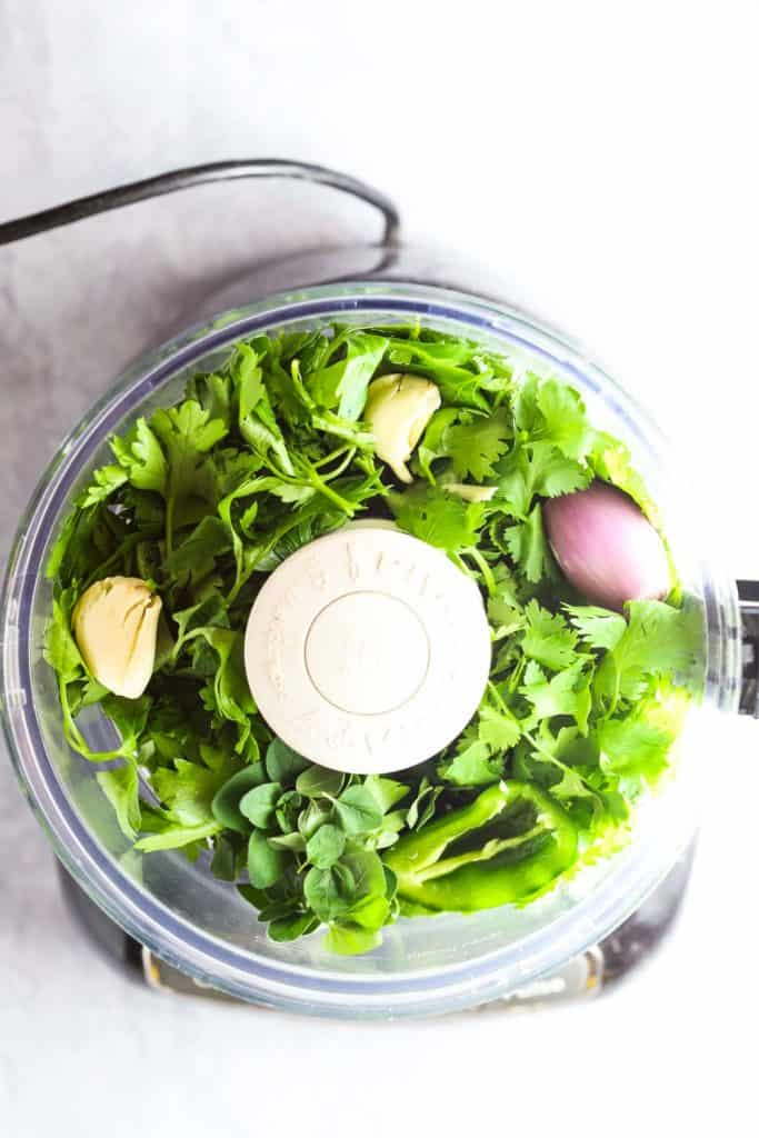Herbs, garlic, and a shallot in a food processor