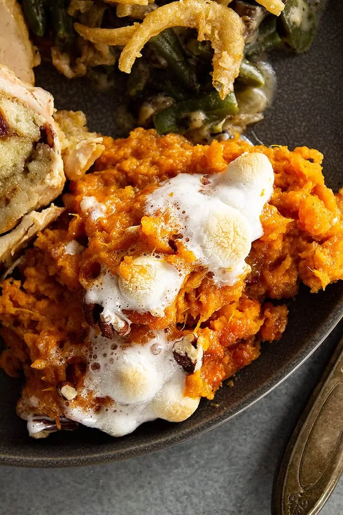 closeup: a generous portion of classic sweet potato casserole with marshmallows on a black plate