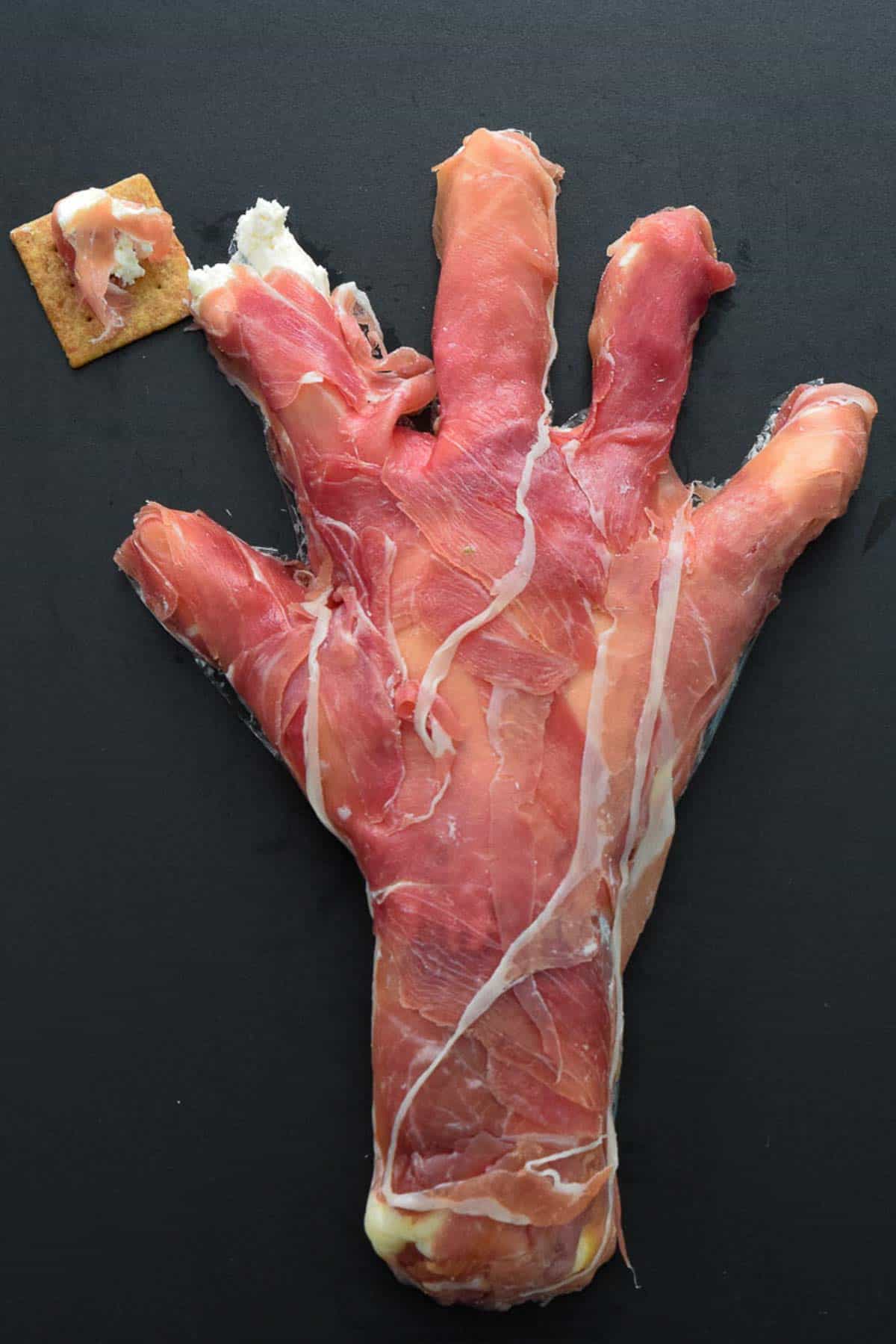 Overhead shot of creepy Halloween hand being served on cracker 