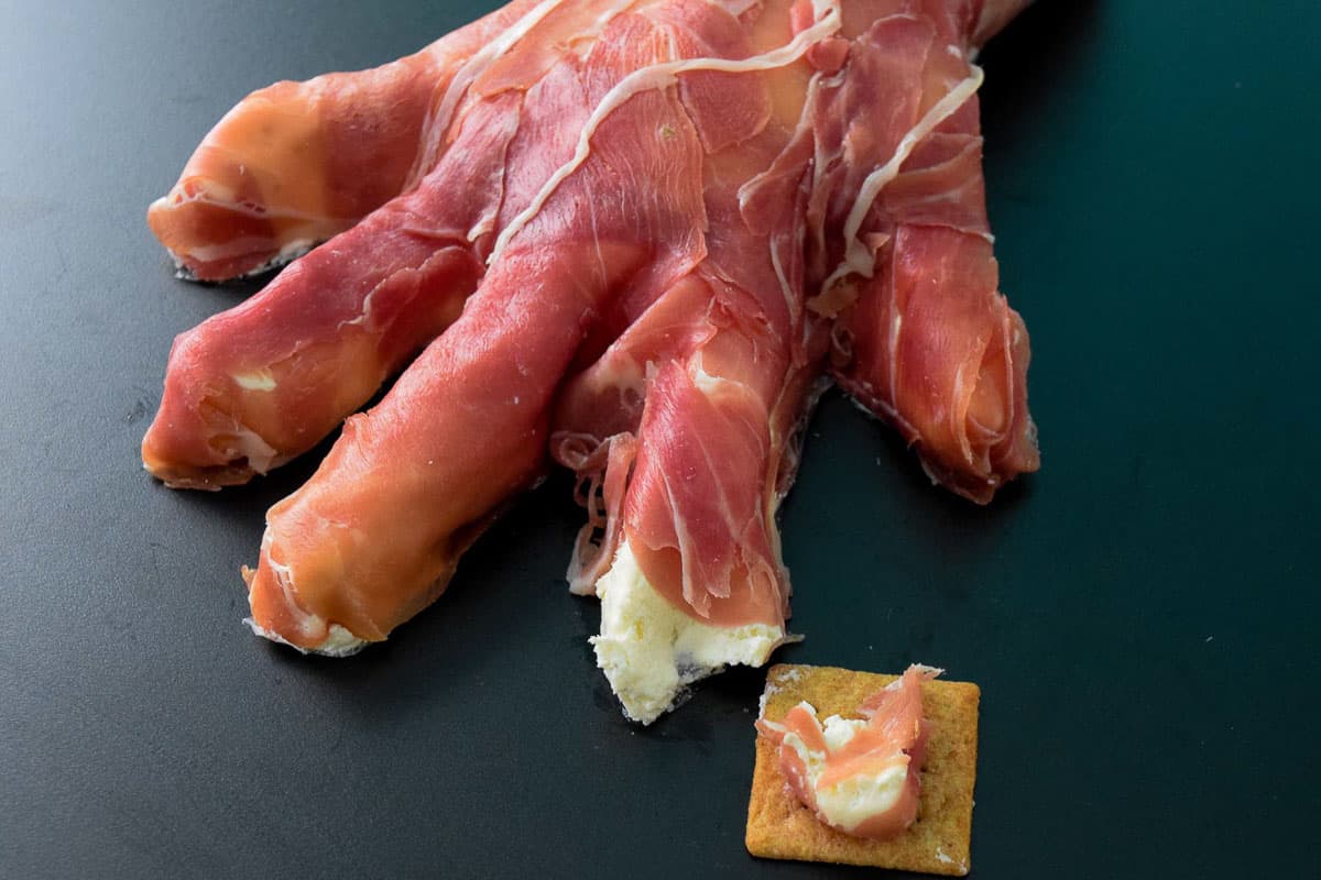 Creepy Halloween Hand with part of index finger missing and served on wheat thin close up view