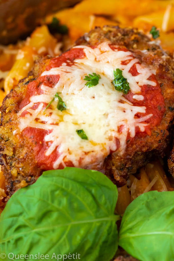 crispy chicken parmesan in a pot of penne alla vodka with basil leaf garnish