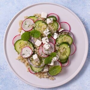 Overhead view of Cucumber Quinoa Salad on a white plate on a light blue background