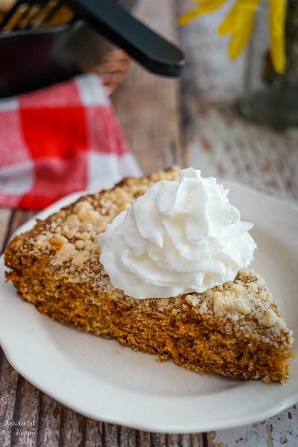 A slice of Molasses Skillet Cake on a plate, topped with a dollop of whipped cream.