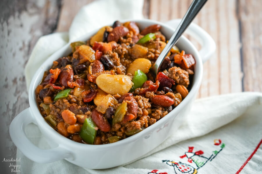 A bowl of Slow Cooker Calico Beans sitting on a napkin with a spoon.