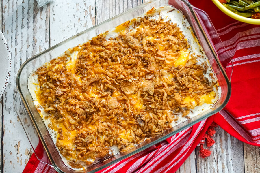 A 9x13 pan of pork chops after they have finished baking on top of a red kitchen towel. 