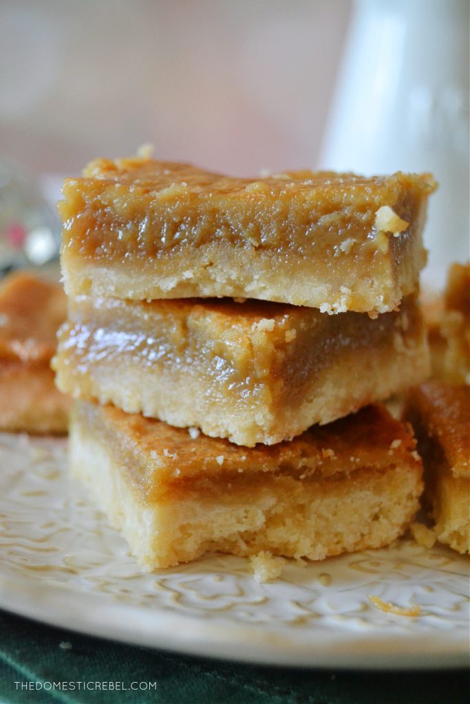 a trio stack of sugar pie squares on a white lacy plate against a light pink background