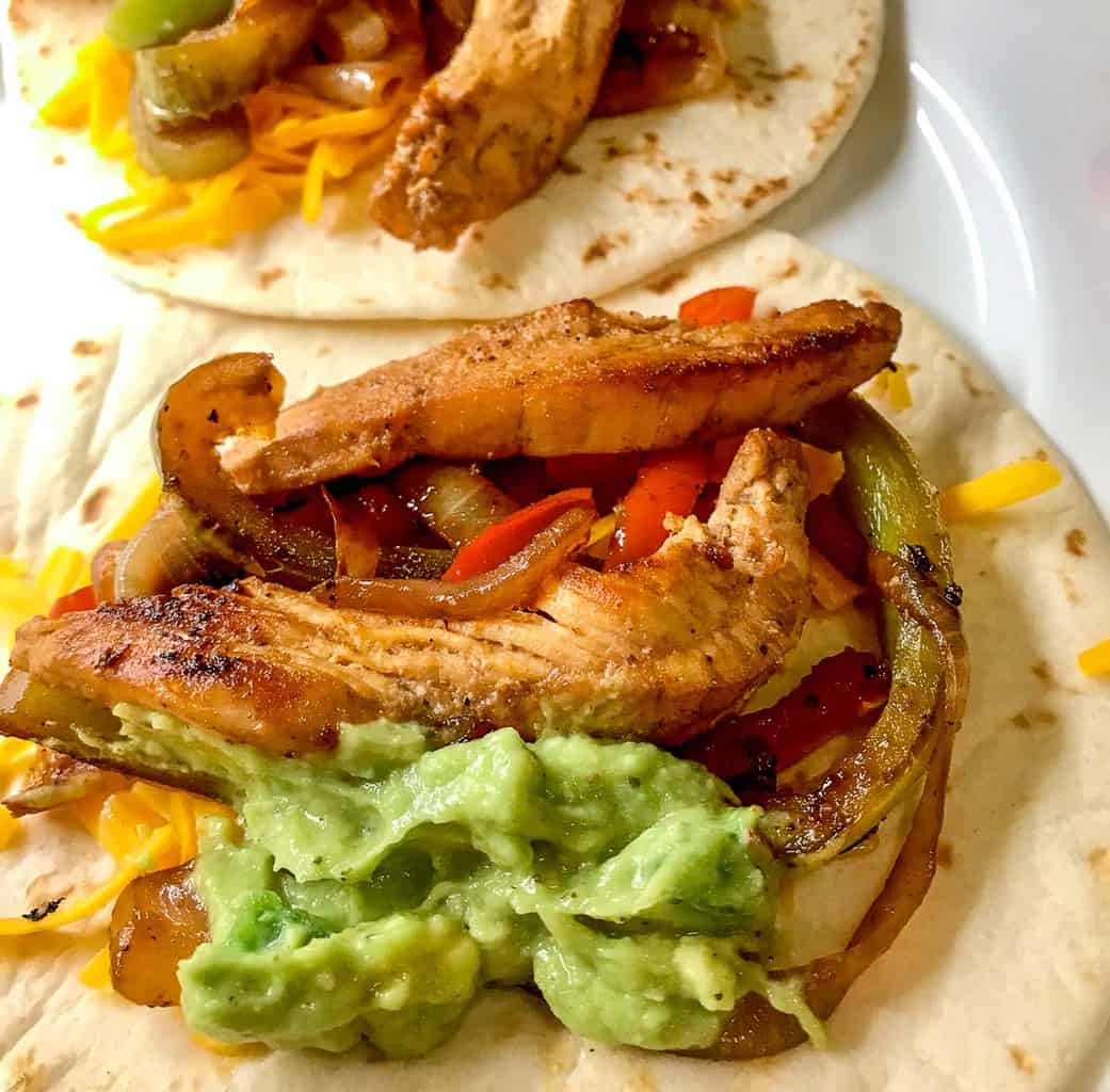 Tex Mex chicken fajitas open faced on a white plate.