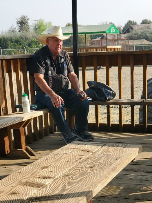 Farmer bob sitting on a wooden bench holding a microphone