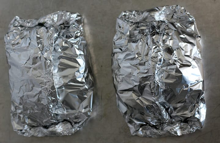 Sealed foil packets on baking sheet with oven baked fish.