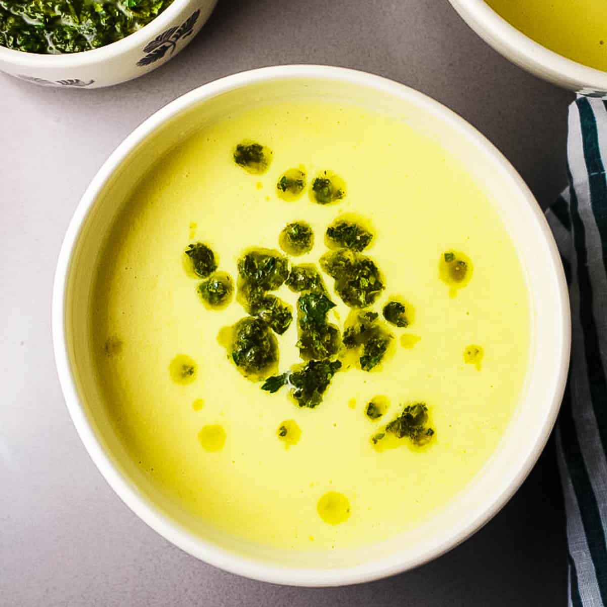 A bowl of creamy corn soup with swirls of chimichurri.