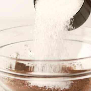 Sugar, butter, cocoa powder in glass mixing bowl.
