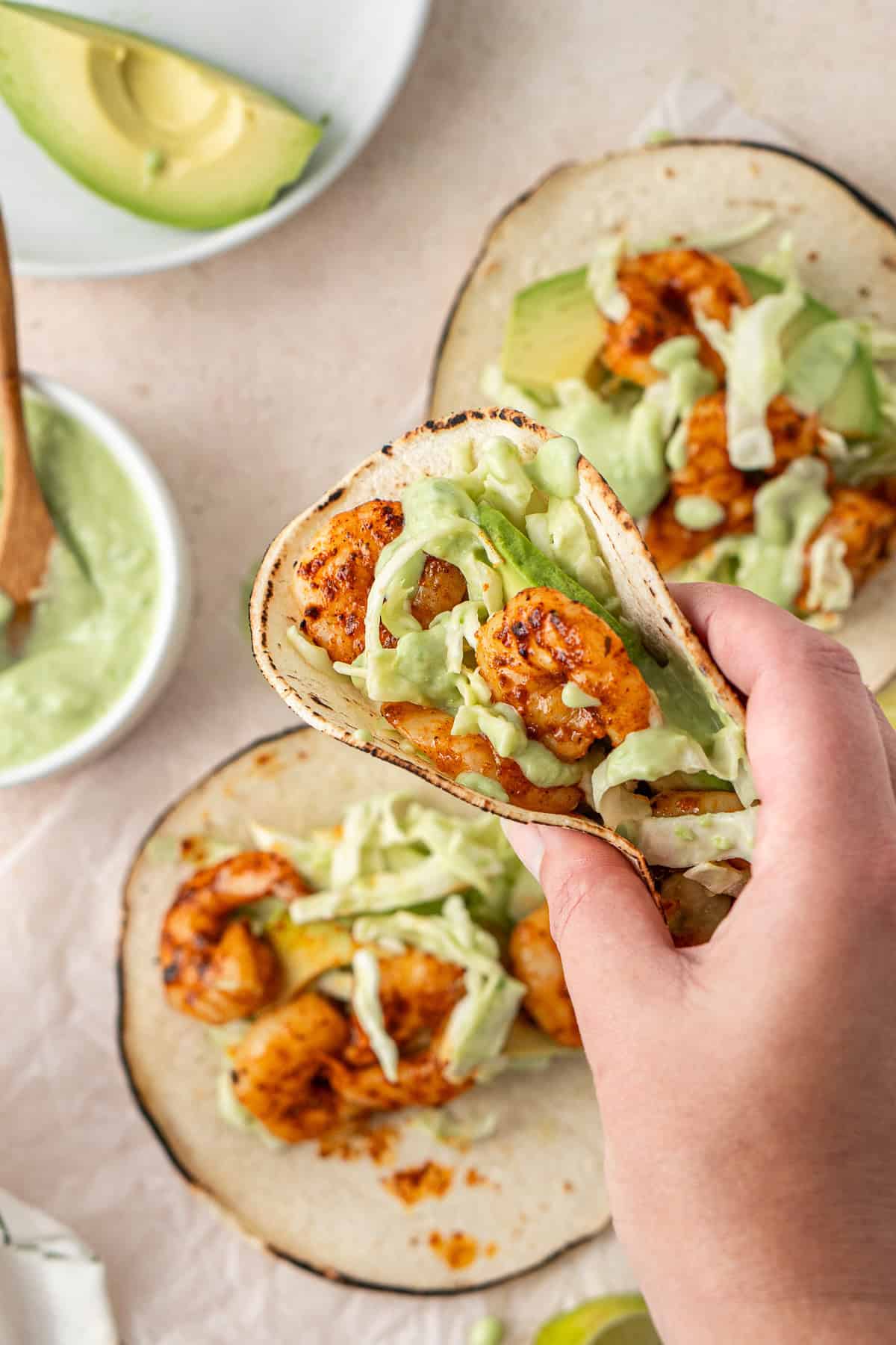 A handing picking up a grilled prawn taco.