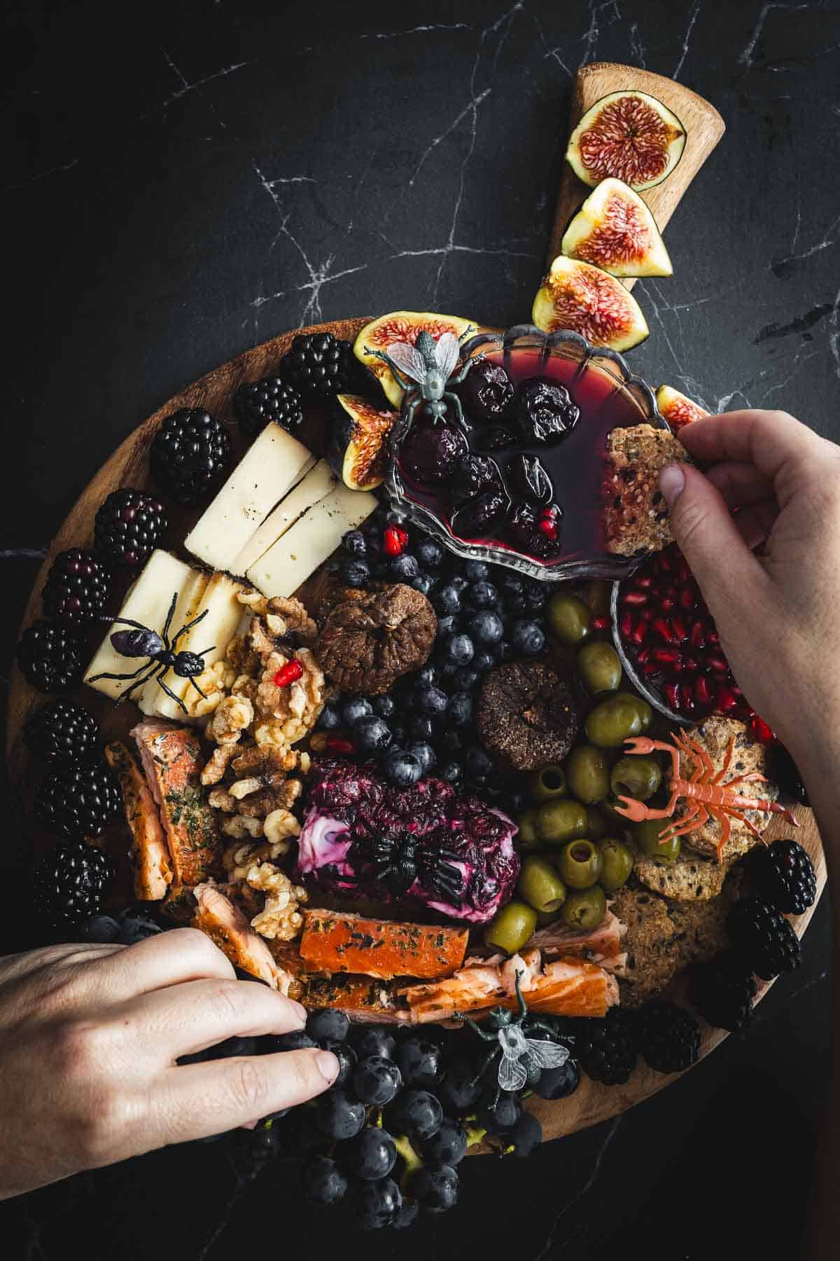 A person holding a platter of fruit and cheese.