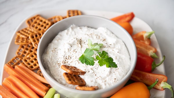 Dip in a bowl served with pretzels and vegetables
