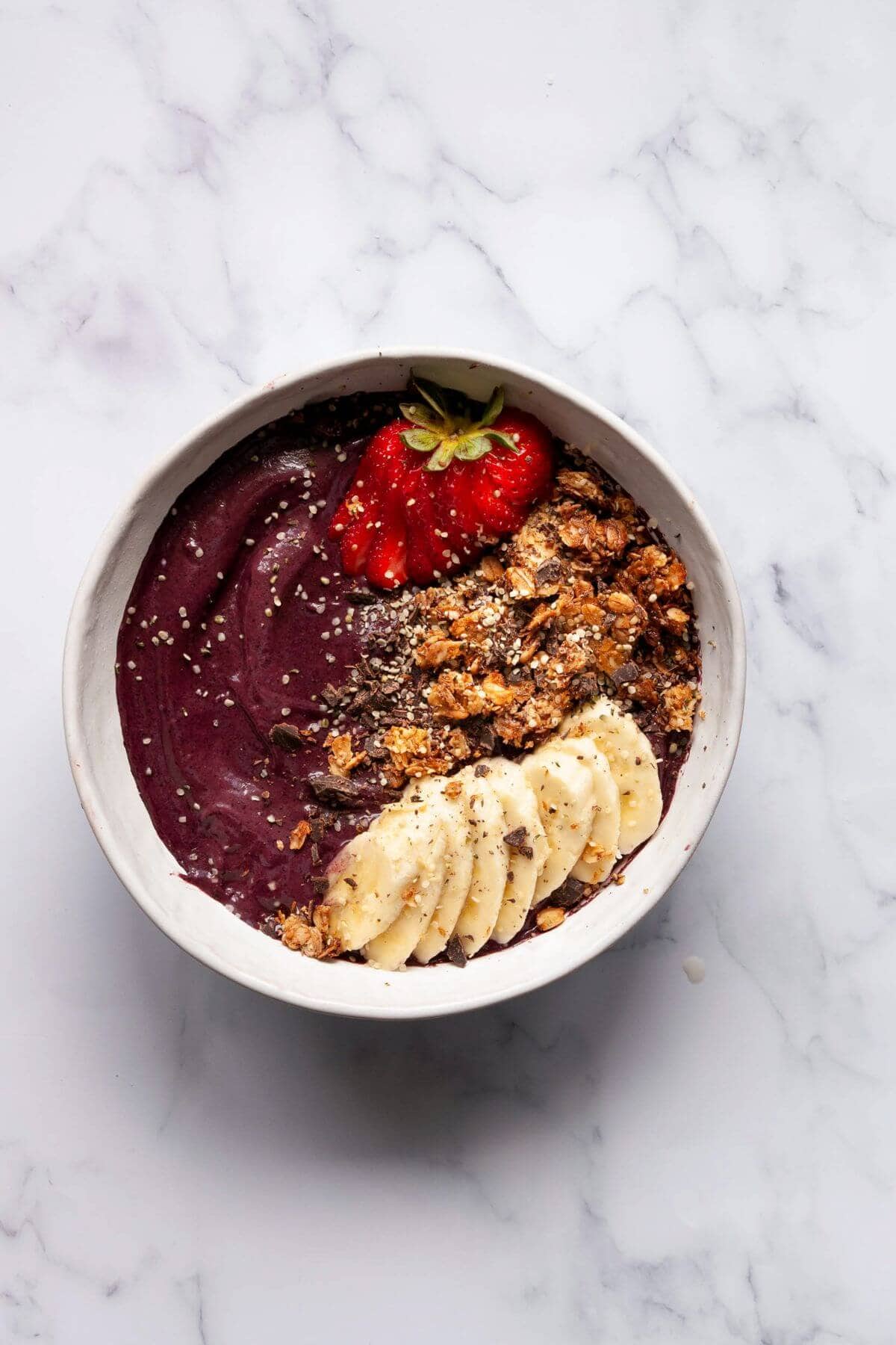 Healthy protein Acai bowl topped with strawberries, sliced bananas, and granola.