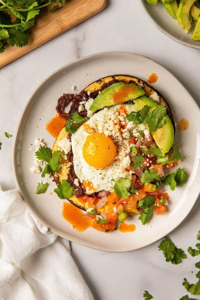 gluten-free huevos rancheros on a plate with avocado and pico de gallo