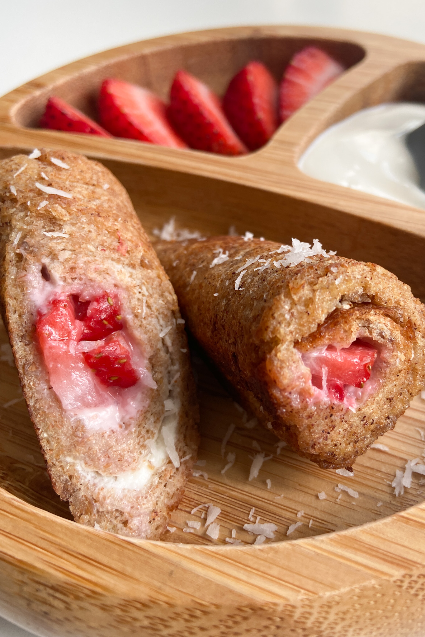 Strawberry cheesecake rollups served with sliced strawberries and yogurt