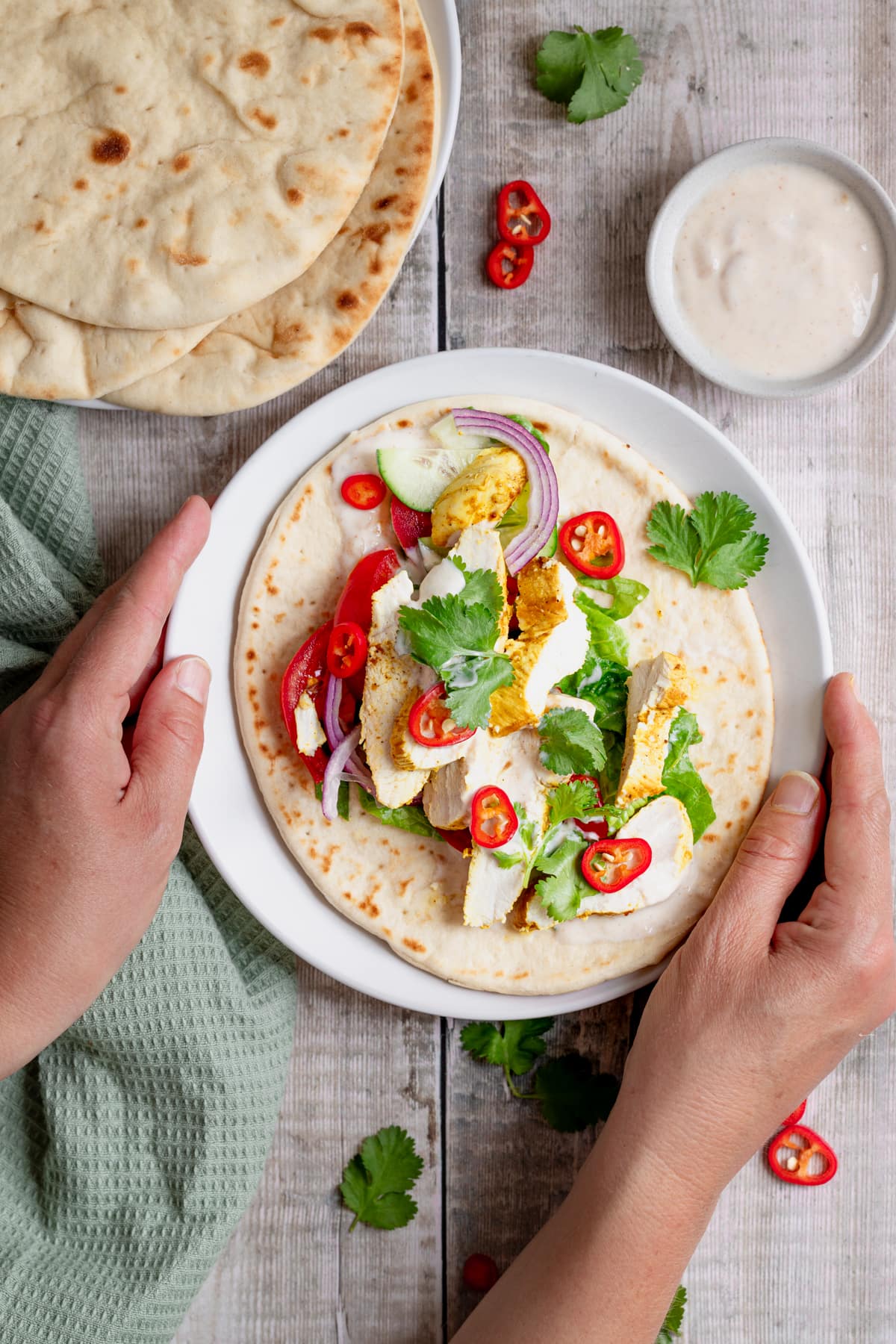 Hands holding a plate of curry chicken wrap