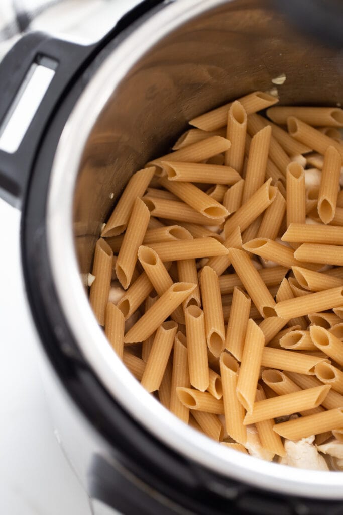Overhead photo of pasta over chicken in an instant pot.