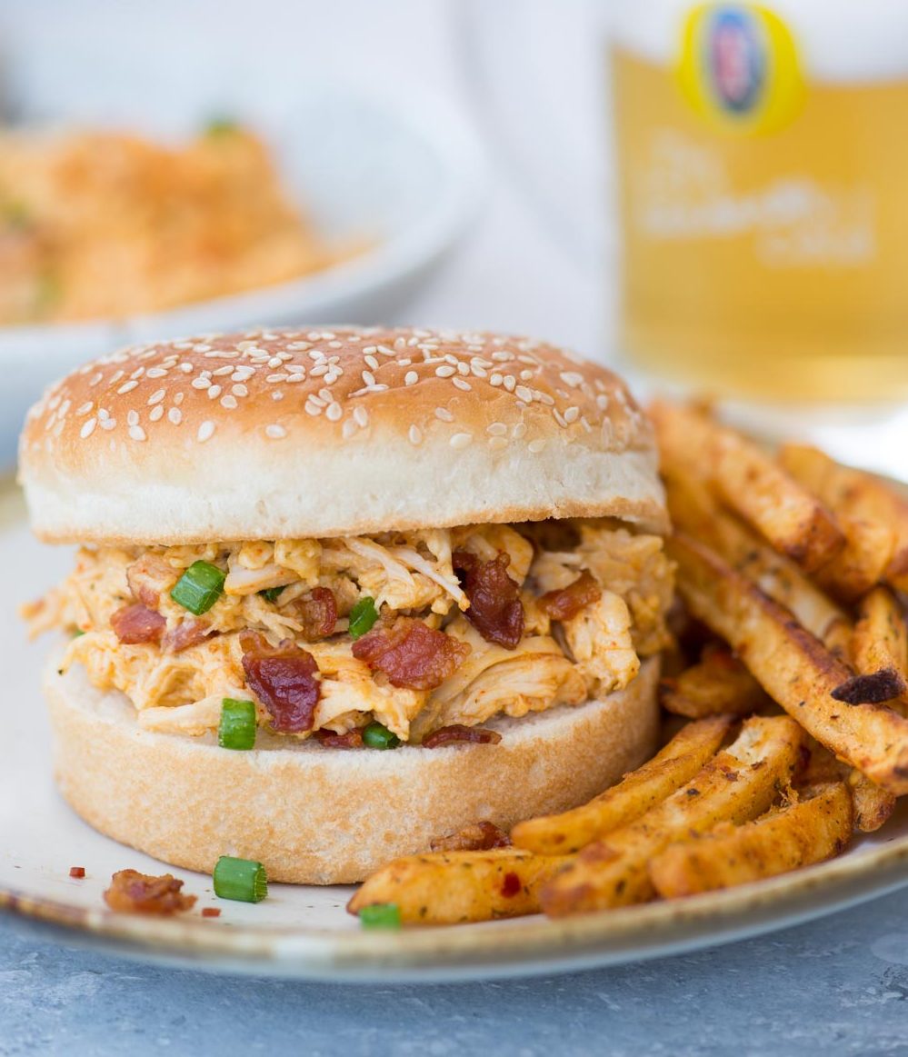 Cheesy and delicious instant pot crack chicken with bun and chips Crack chicken with bacon served in a bun alongside chips