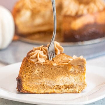 slice of pumpkin cheesecake on a white plate with the rest of the cheesecake behind it