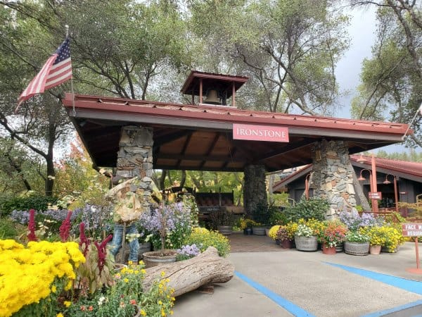 Ironstone winery sign over the entrance to the winery with buckets of flowers and plants