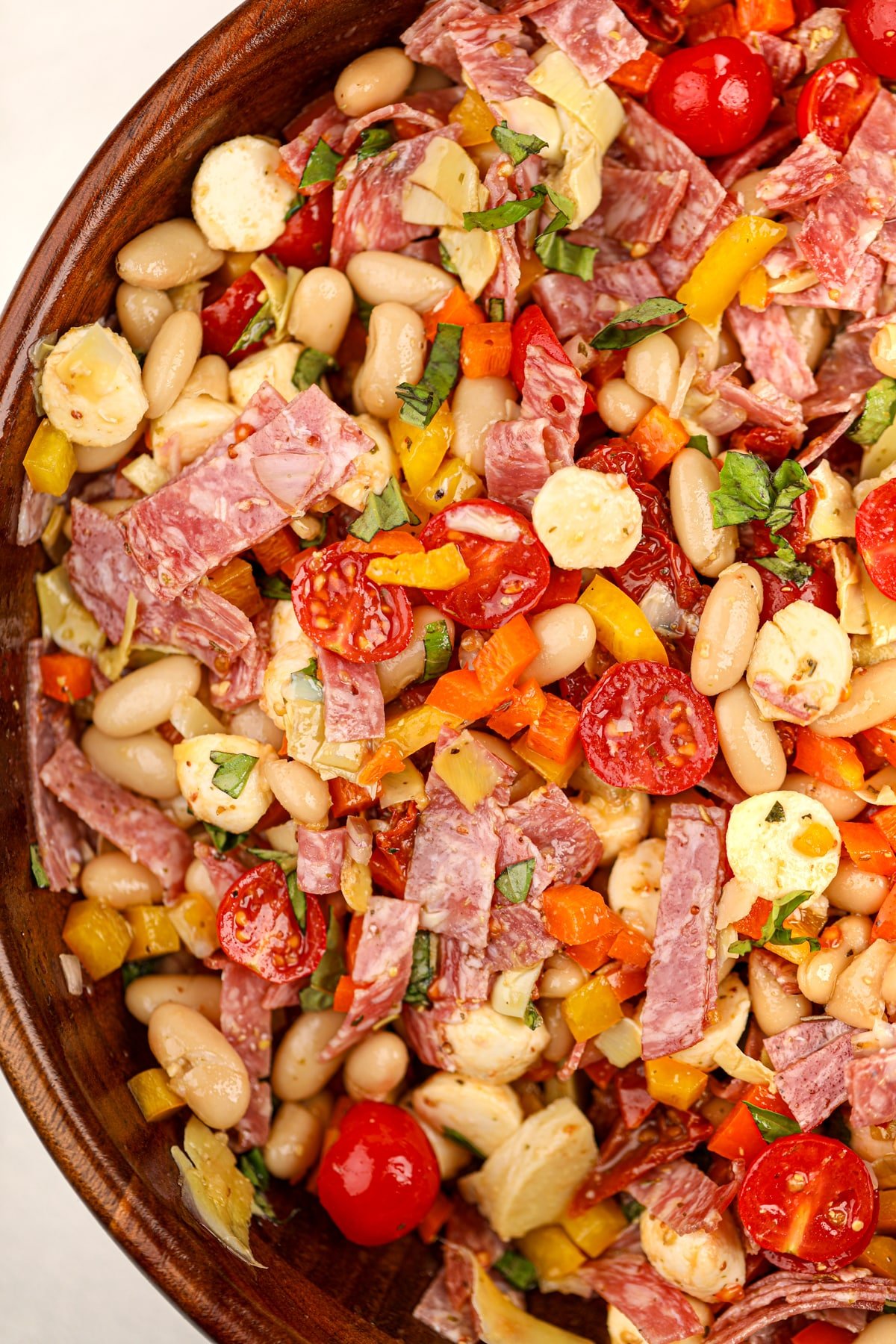 A wooden bowl filled with a colorful bean salad.