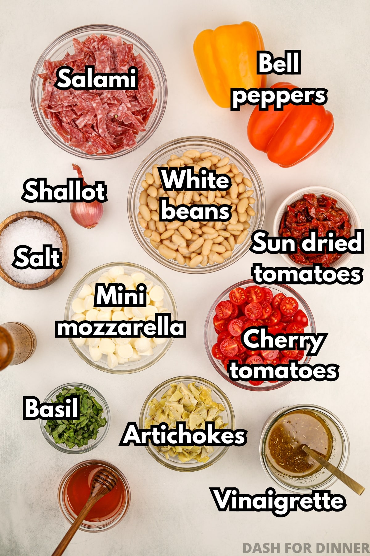The ingredients needed to make Italian bean salad, including salami, mozzarella, sundried tomatoes, and more.