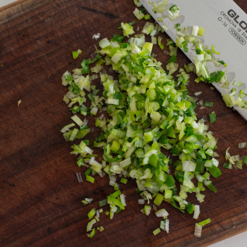 Green onion finely chopped with a knife on a wooden board