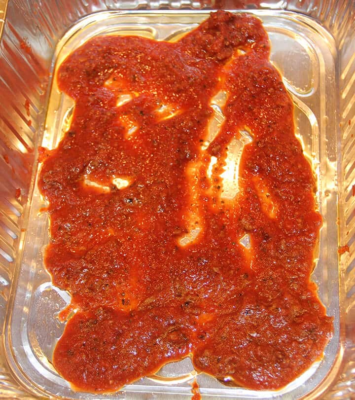 Sauce spread in pan to make lasagna without ricotta.