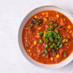 An overhead view of the Leftover Chicken Soup with Veggies in a white bowl.