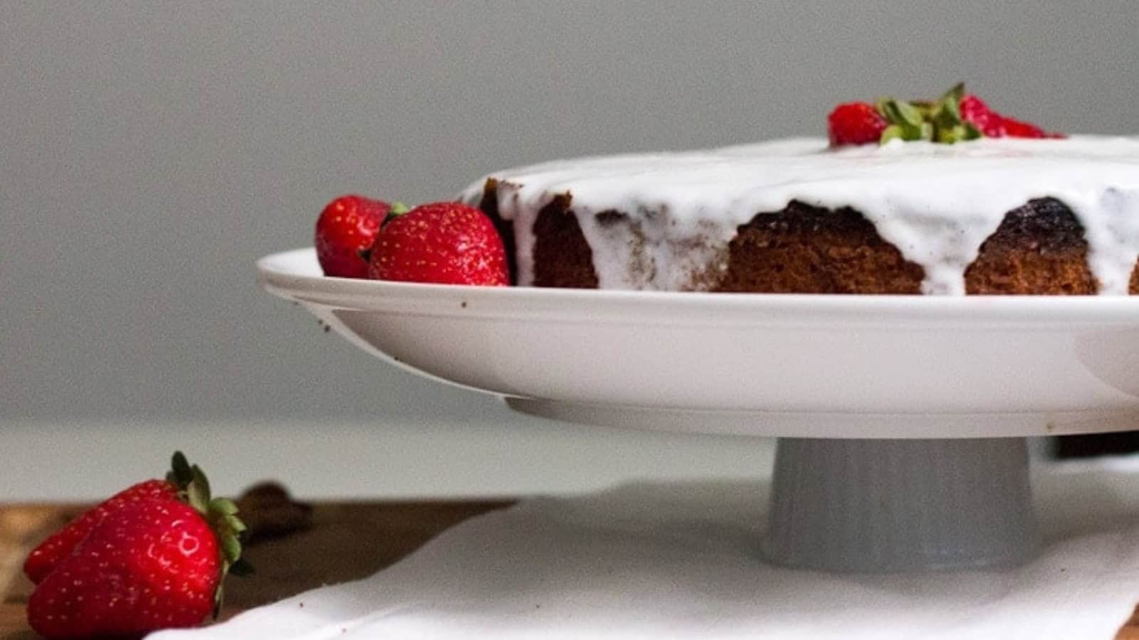 A slice of strawberry cake on a plate next to strawberries.