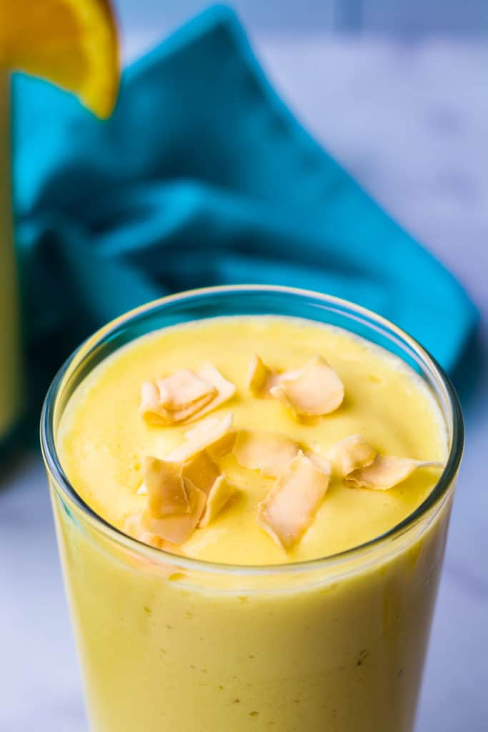 A mango pineapple smoothie garnished with coconut chips